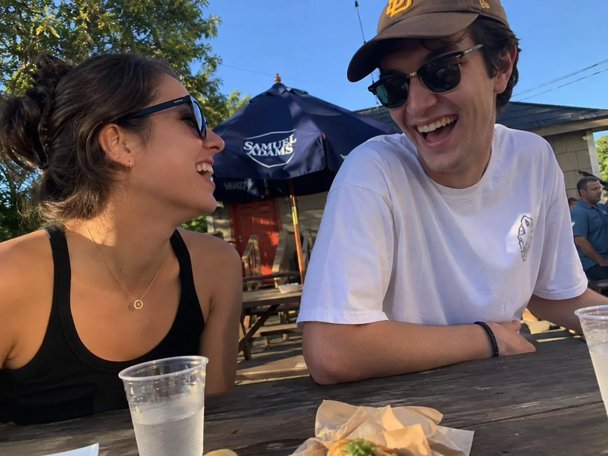 Two friends laughing at an outdoor table